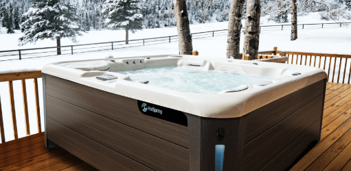 A steaming Hot Spring Highlife hot tub sits invitingly on a deck blanketed in snow.