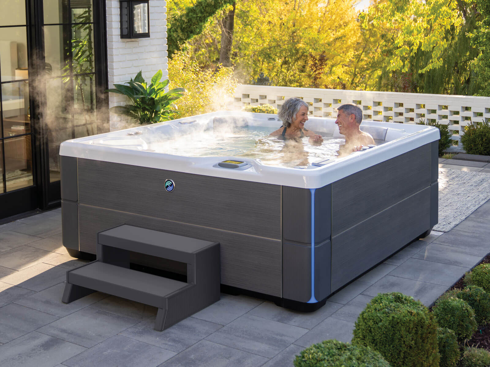 A luxurious Hot Spring Highlife Aria hot tub in a serene backyard setting, perfect for relaxation.