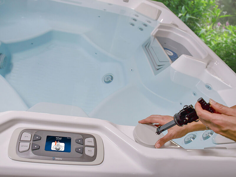 Close-up of a hand replacing the freshwater salt system cartridge of their Hot Spring Spas hot tub