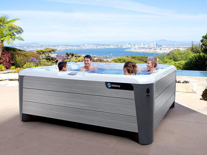 A group of four friends enjoying a relaxing soak in salt water hot tub, laughing and unwinding as they take in the stunning ocean view in the background.